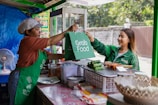 a woman handing a green bag to another woman