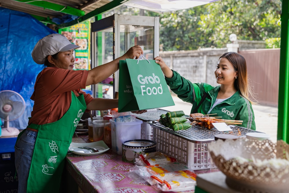 a woman handing a green bag to another woman