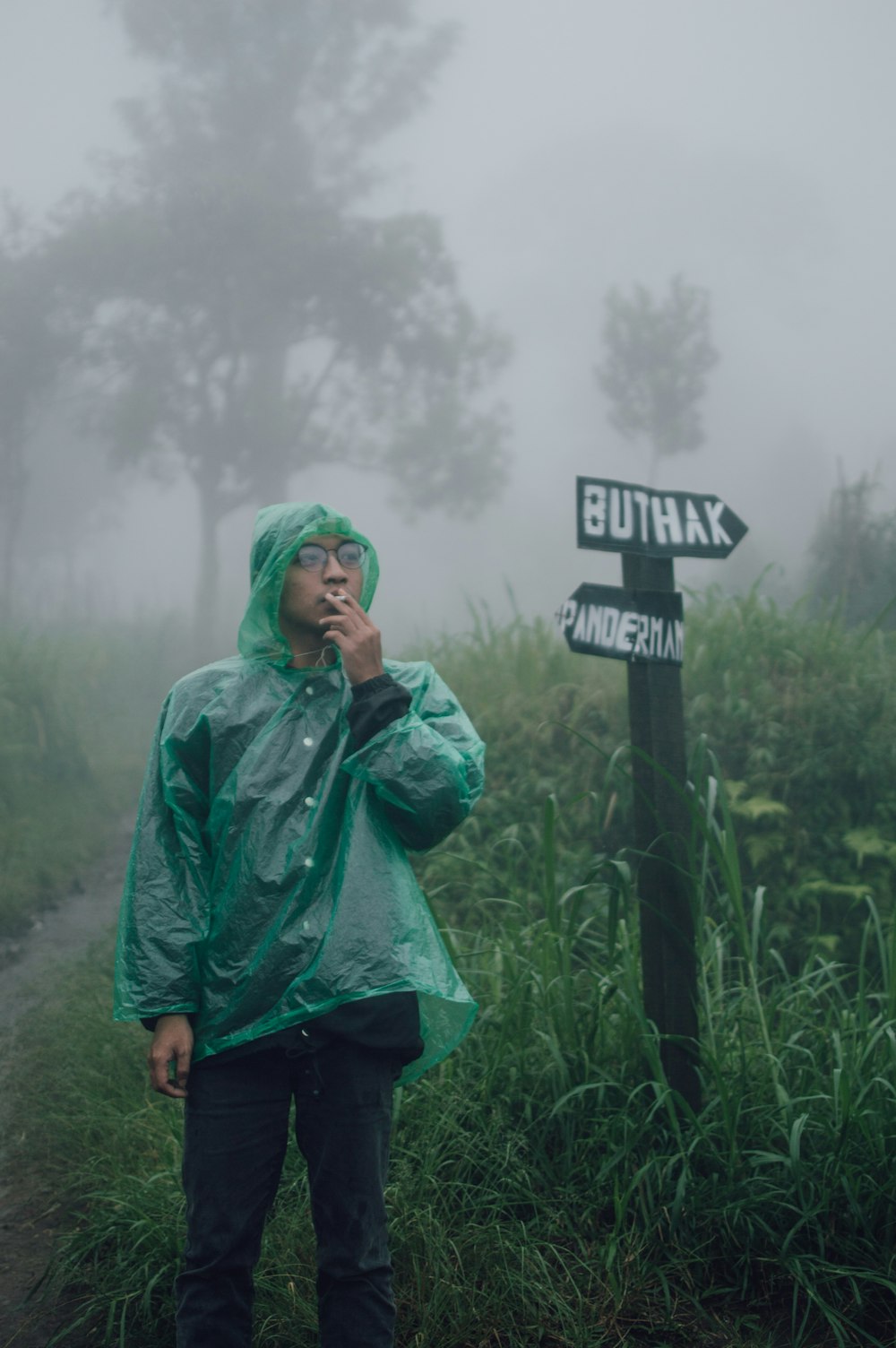 a man in a rain coat standing next to a sign