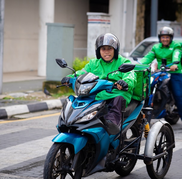 a man riding a blue motorcycle down a street