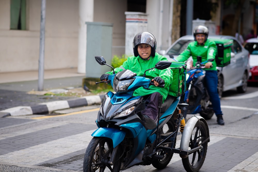 a man riding a blue motorcycle down a street