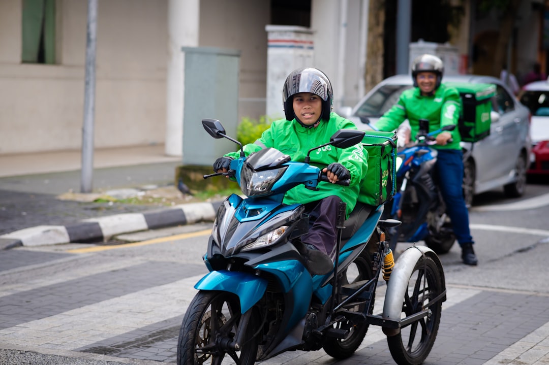a man riding a blue motorcycle down a street,