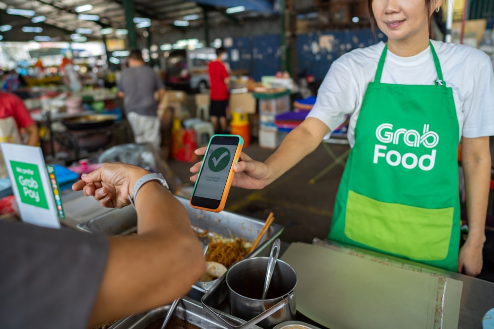 a man in a green apron holding a cell phone