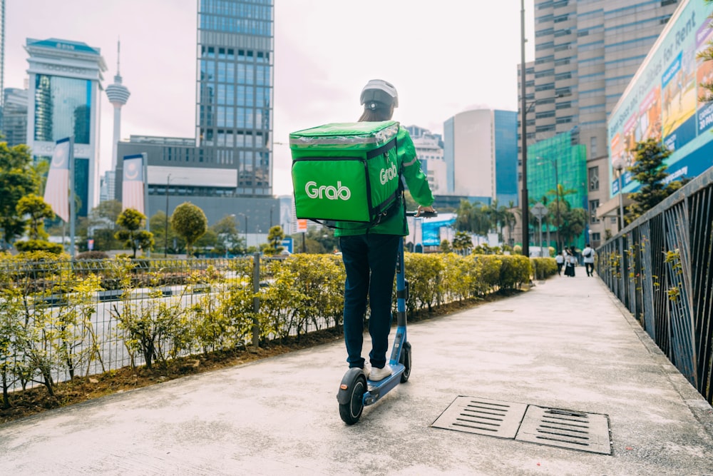 a man riding a scooter with a green box on his back
