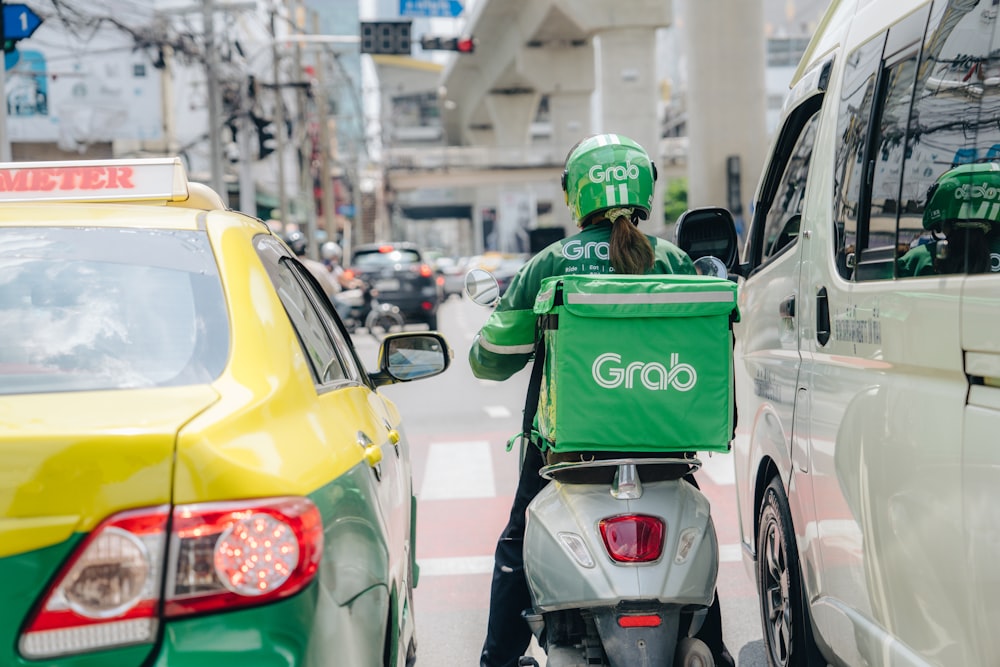 a person riding a scooter with a green bag on the back of it