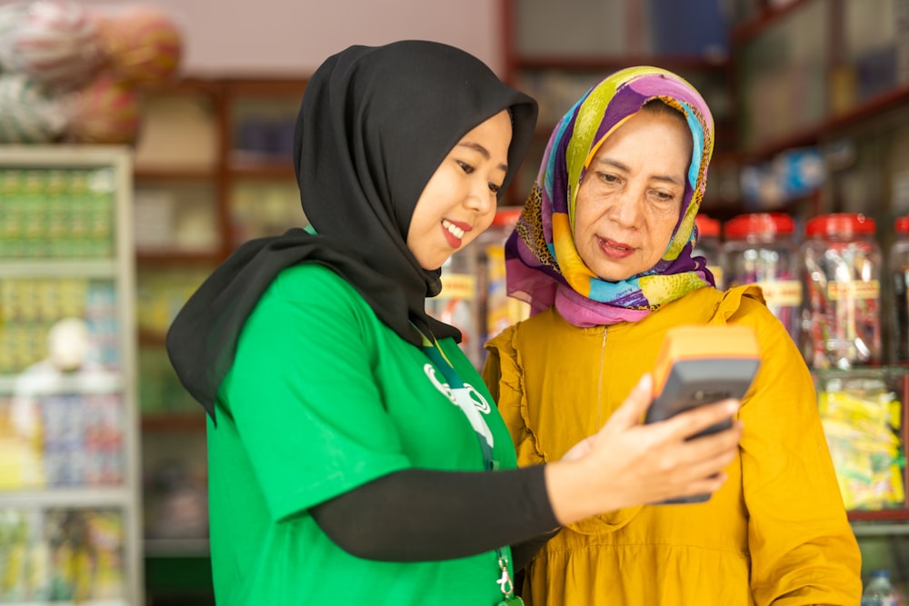 two women standing in a store looking at a cell phone