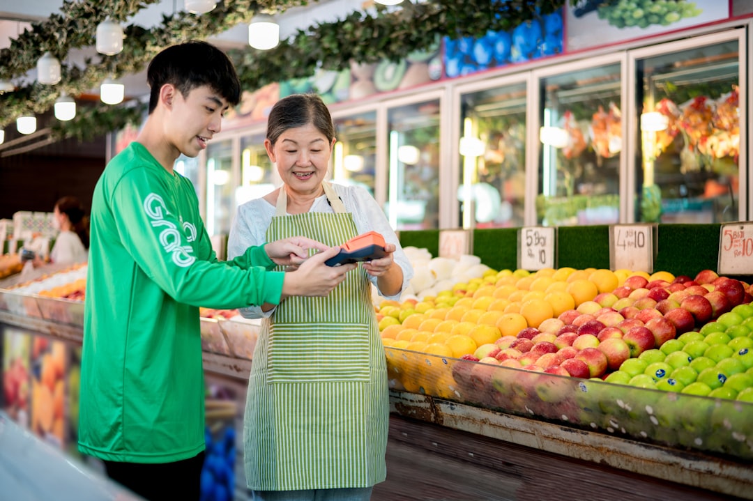 a man and a woman standing in front of a fruit stand,
