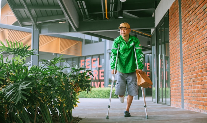 a man with crutches walking down a sidewalk