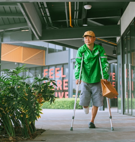 a man with crutches walking down a sidewalk