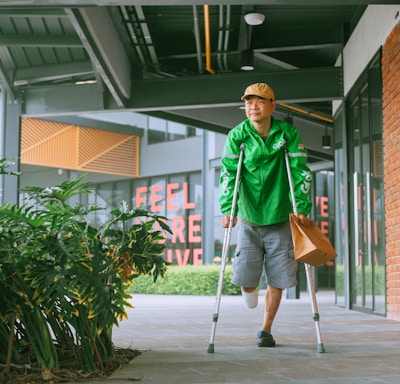 a man with crutches walking down a sidewalk