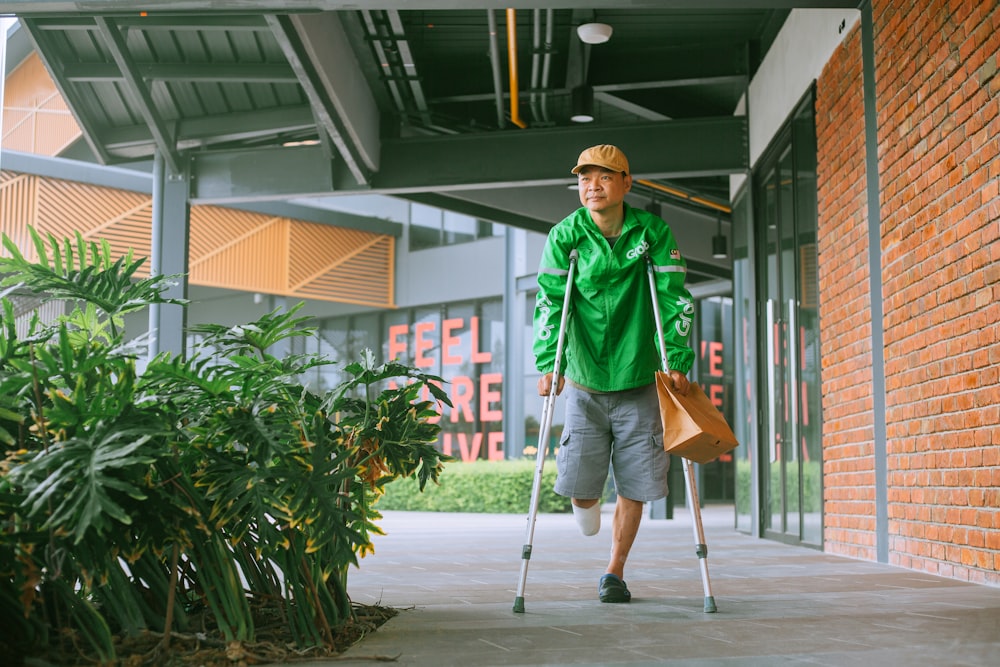 a man with crutches walking down a sidewalk