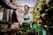 a man holding a paper bag in front of a bunch of bananas