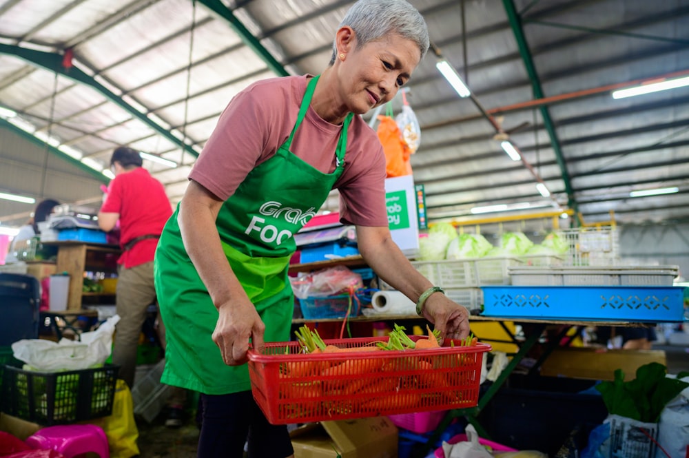 a woman in a green apron holding a red basket