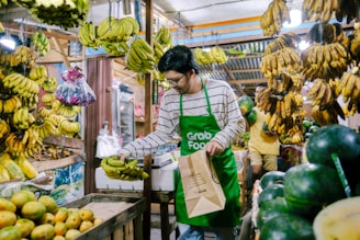 a man in an open market holding a paper bag