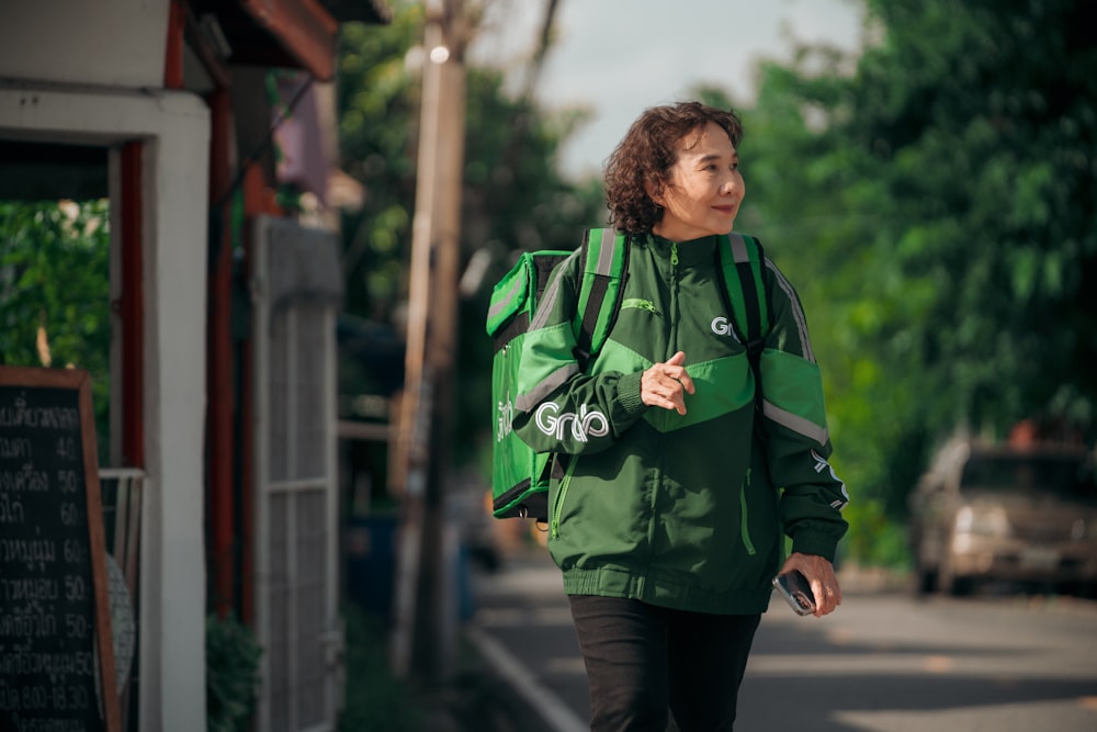 a woman in a green jacket walking down a street