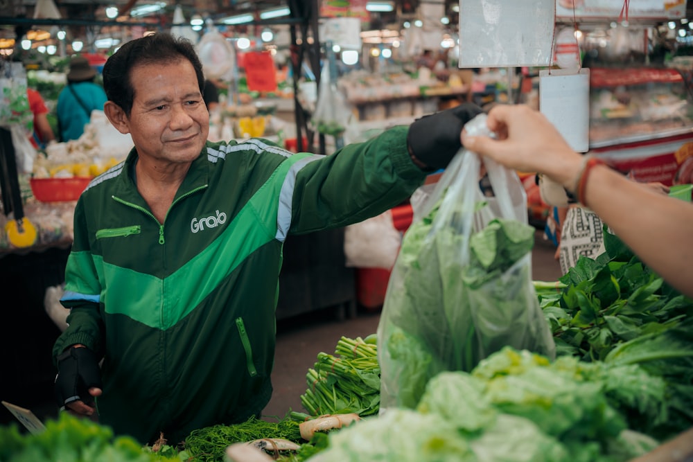 Un hombre sosteniendo una bolsa de lechuga en un mercado
