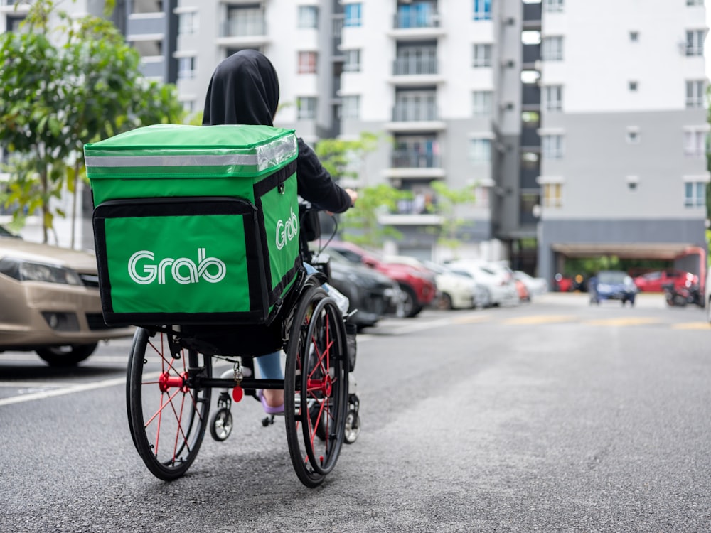 a person riding a bike with a green box on the back