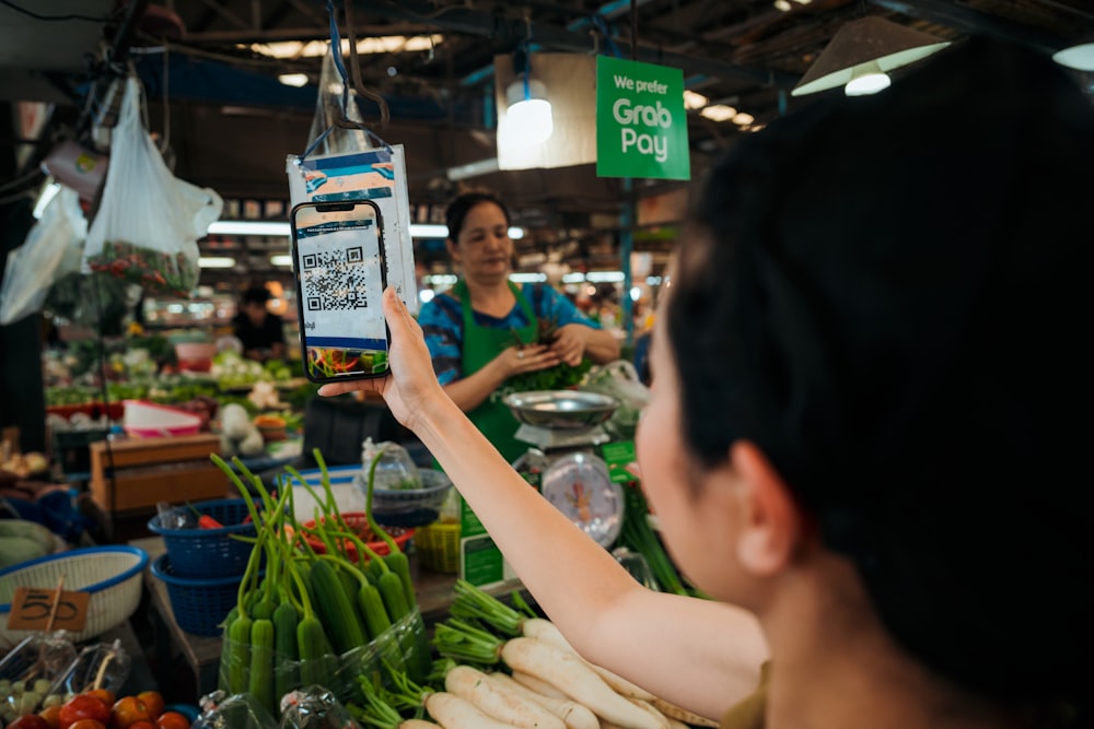 a woman holding up a smart phone in a market