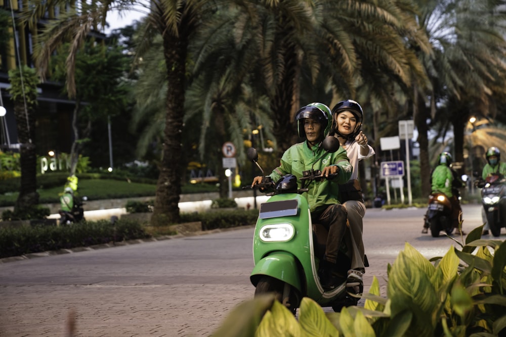 a couple of people riding on the back of a green scooter