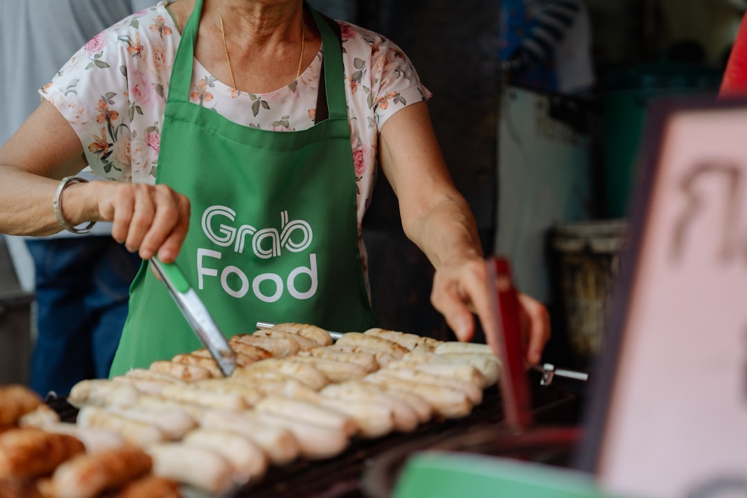 a woman in an apron is cooking donuts on a grill,
