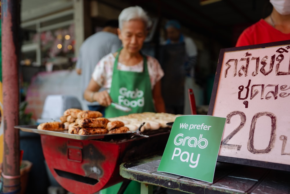 a woman in a green apron standing next to a tray of food