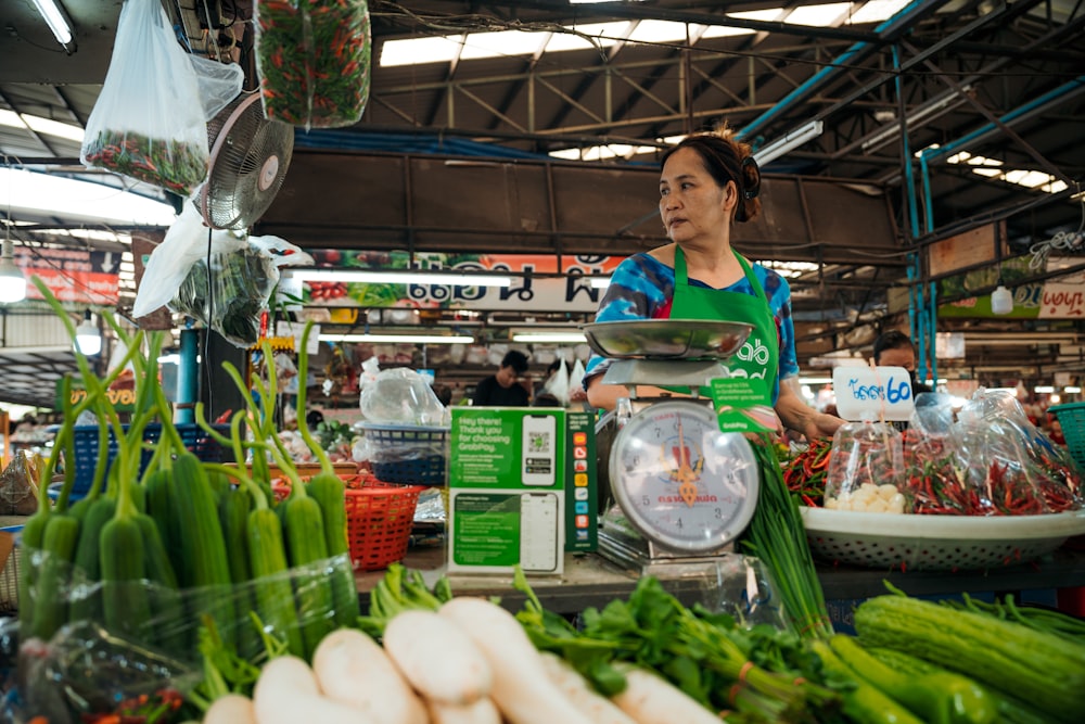 a woman standing in front of a display of vegetables