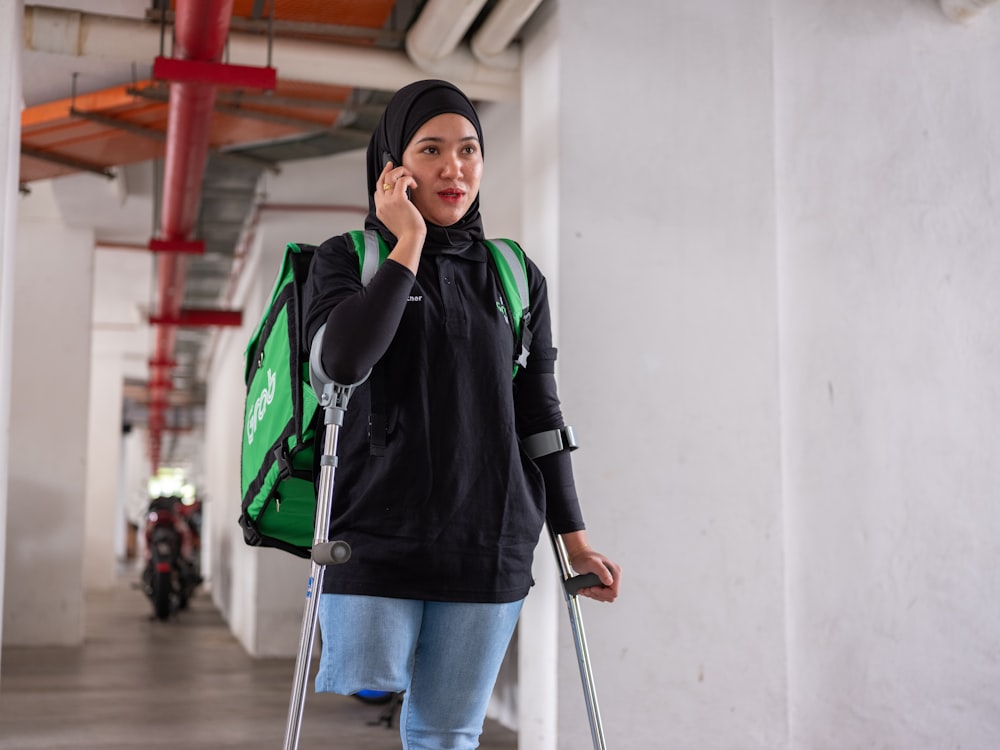 a woman walking down a hallway while talking on a cell phone