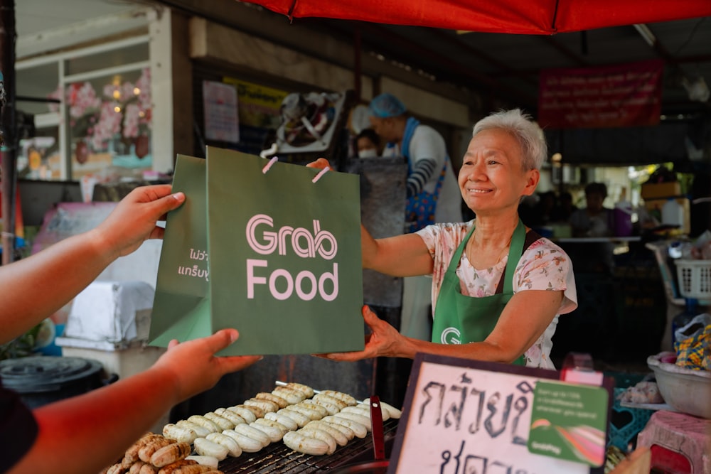 a woman holding up a sign in front of a food stand