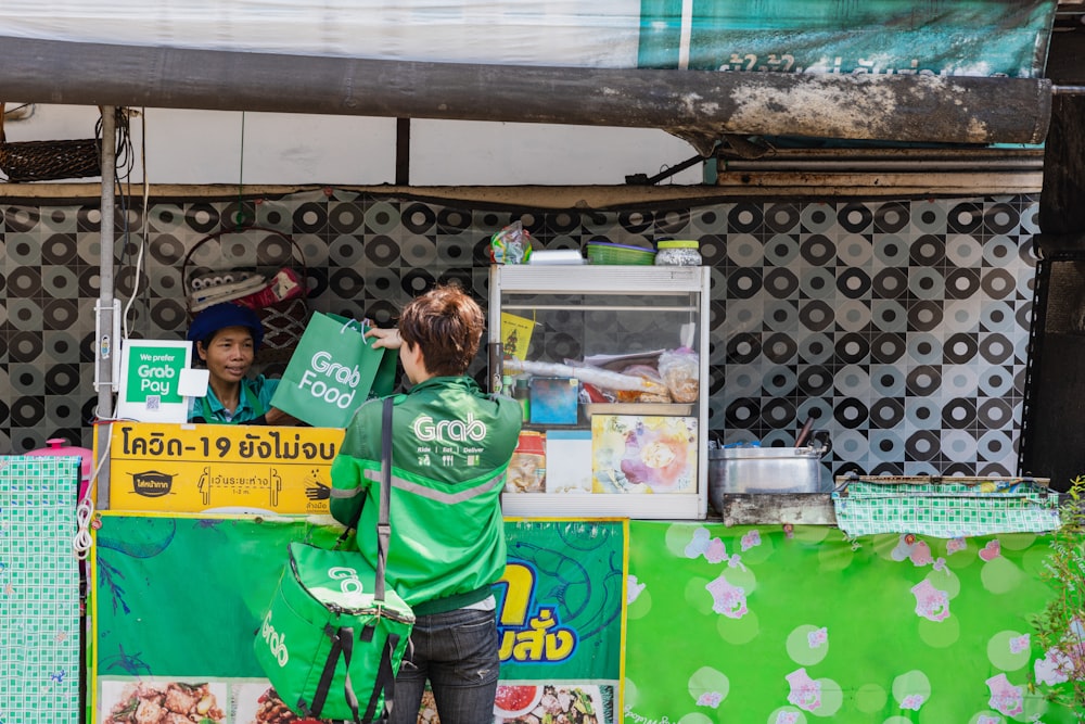 a man standing next to a green food stand