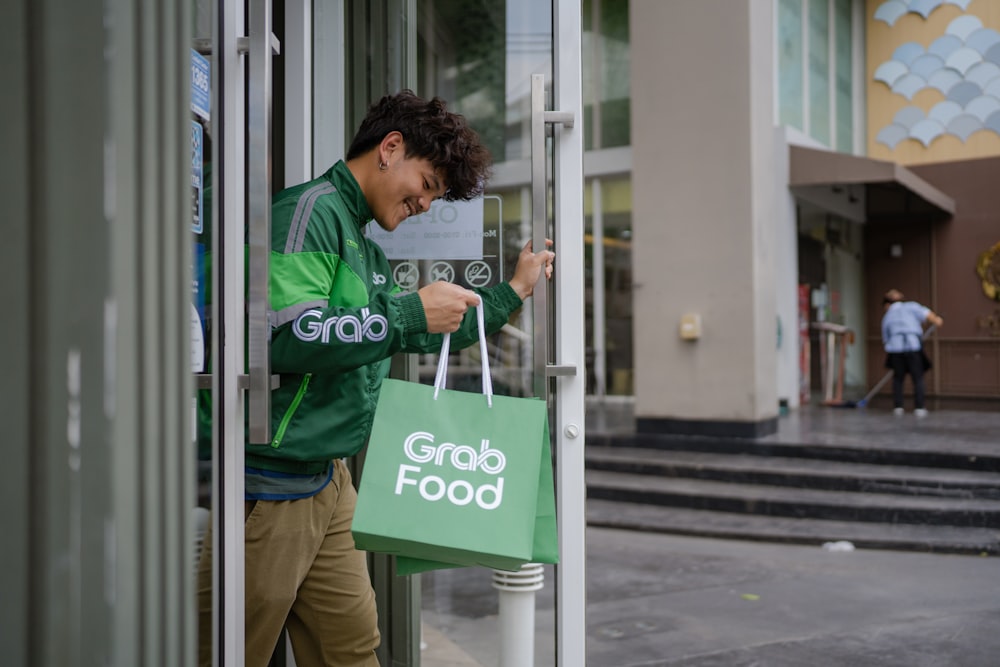 a man holding a green bag and entering a store