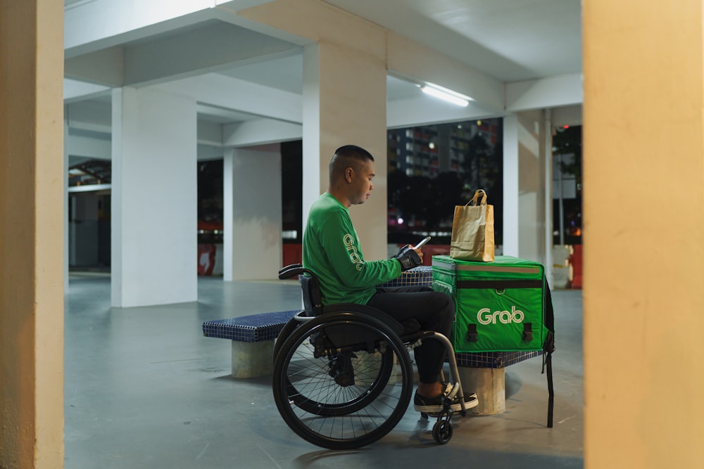 Un hombre con una camisa verde sentado en una silla de ruedas