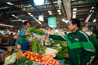 Farmers and exporters shaking hands over a digital tablet in a sunny outdoor market.