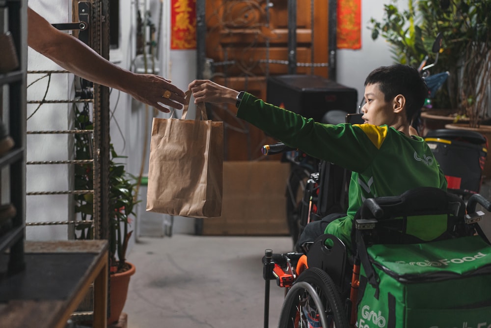 a man in a wheel chair handing a bag to another person