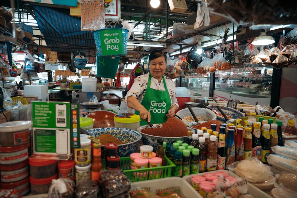 a woman standing behind a counter filled with food