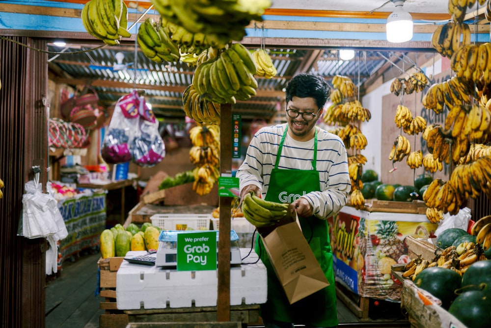 a man holding a bag of bananas in a store