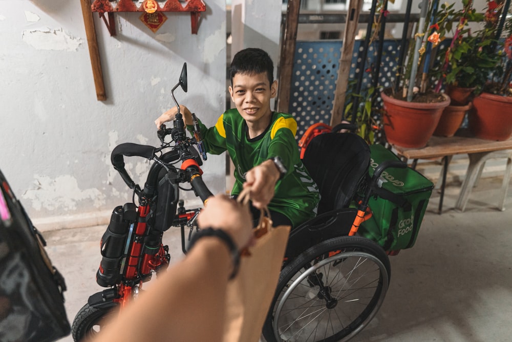 Un garçon en chemise verte assis dans un fauteuil roulant