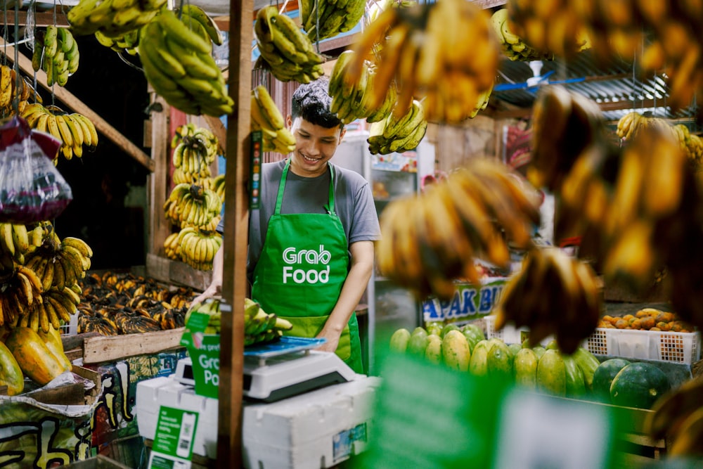 a man standing in front of a bunch of bananas