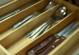A wooden cutlery holder filled with neatly arranged forks, knives, and spoons.