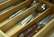 A wooden cutlery drawer organizer contains various silver utensils, including knives, forks, and spoons, neatly arranged in separate compartments. A knife with a wooden handle is prominently visible.