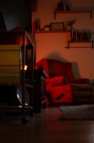 a red chair sitting in a living room next to a fire place