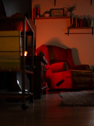 a red chair sitting in a living room next to a fire place