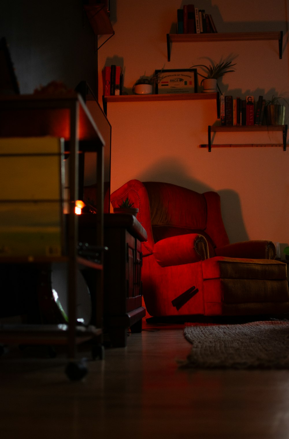 a red chair sitting in a living room next to a fire place