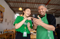 An Asian female and Caucasian male couple smiling confidently while using a mobile app together.
