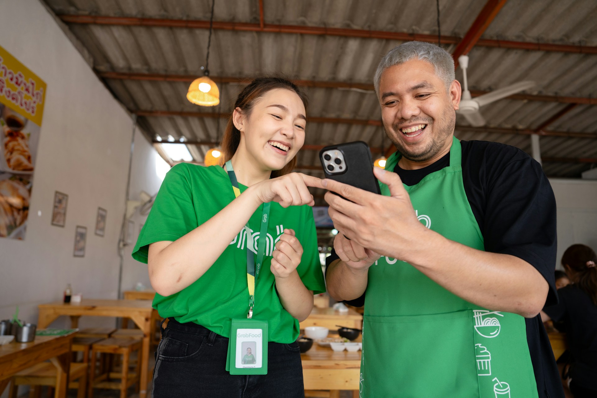 a man and woman in green aprons looking at a cell phone
