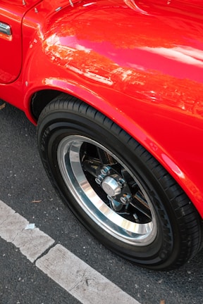 Close-up of a shiny red hatchback with polished rims displayed outdoors.