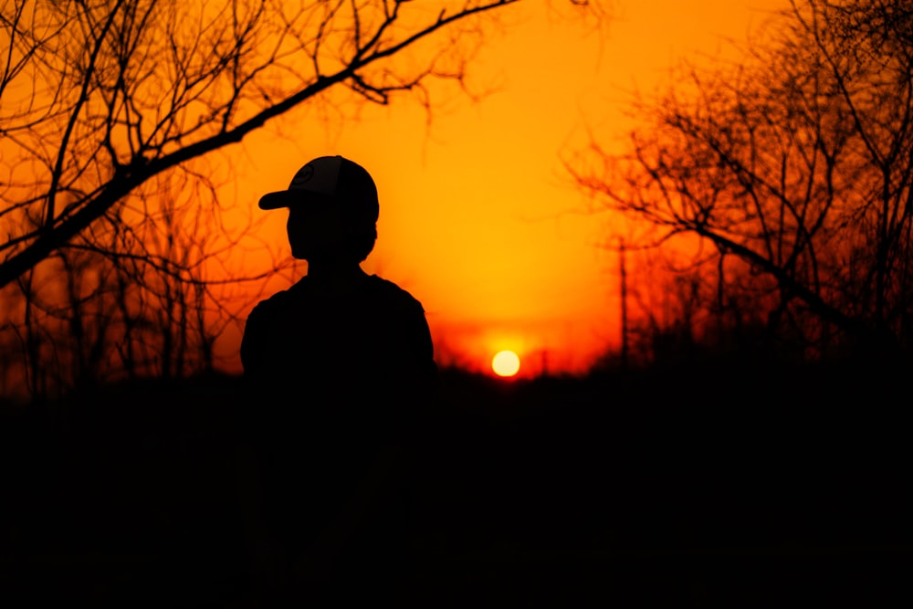 a silhouette of a person wearing a helmet at sunset
