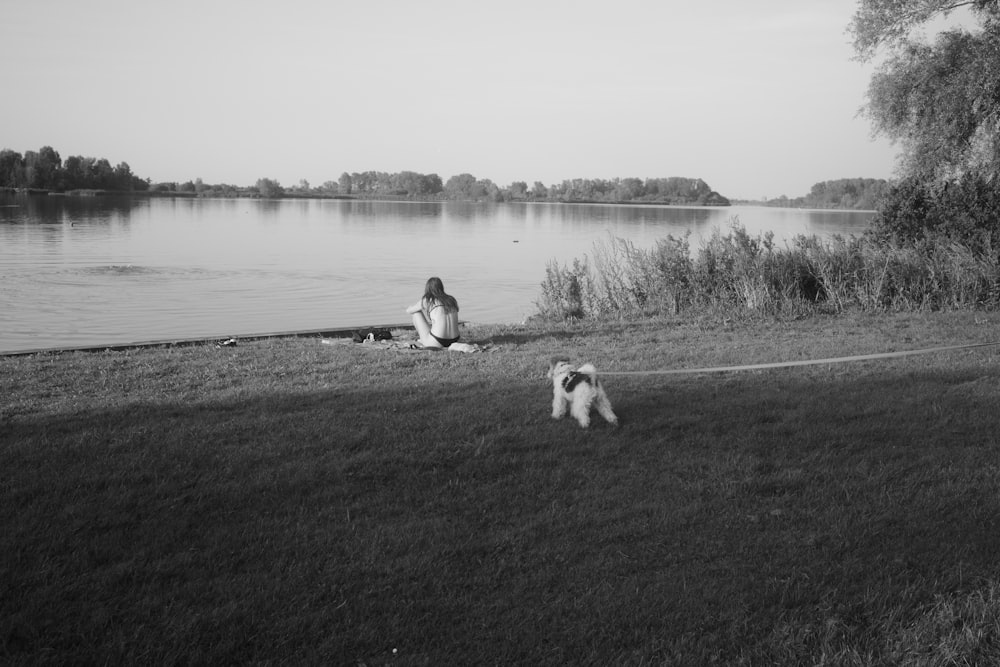 a woman sitting on the grass next to a dog