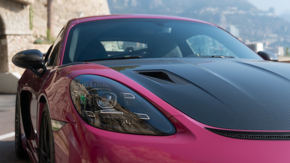a pink sports car parked on the side of the road