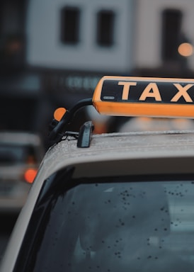 Close-up of a sleek orange and navy taxi sign on a car roof in Lisbon.