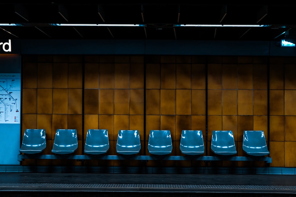 a row of blue chairs sitting in front of a wall